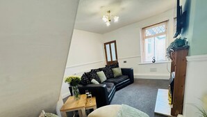 A living room with a sofa, a coffee table, and a window with blinds.