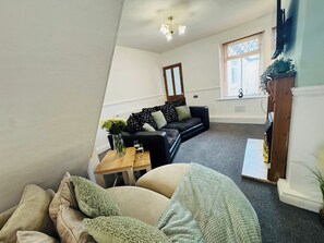 A living room with a sofa, a coffee table, and a window with blinds.