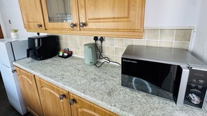A kitchen with wooden cabinets, a microwave, a coffee maker, and a kettle.