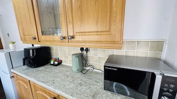 A kitchen with wooden cabinets, a microwave, a coffee maker, and a kettle.