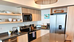Una cocina moderna con electrodomésticos de acero inoxidable, armarios de madera y una isla central con taburetes de bar.