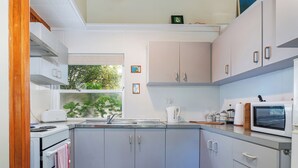A compact kitchen with a window, a kettle, a microwave, and a toaster.