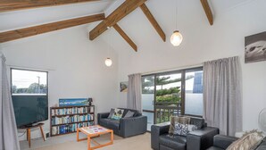 A spacious living room with a large bookshelf, two sofas, a coffee table, and a large window offering a view of the outdoors.