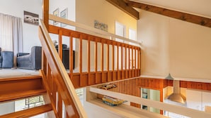A wooden staircase leading to a loft bedroom with a view of the outdoors.