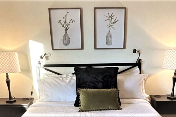 A neatly made bed with white and green pillows, two framed botanical prints on the wall, and bedside lamps on either side. - Large Home Near Boulder Fenced Yard 2 Dogs OK (Longmont)