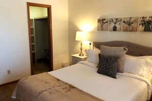 A neatly made bed with a patterned pillow, a bedside lamp, and a wall with framed artwork. - Large Home Near Boulder Fenced Yard 2 Dogs OK (Longmont)