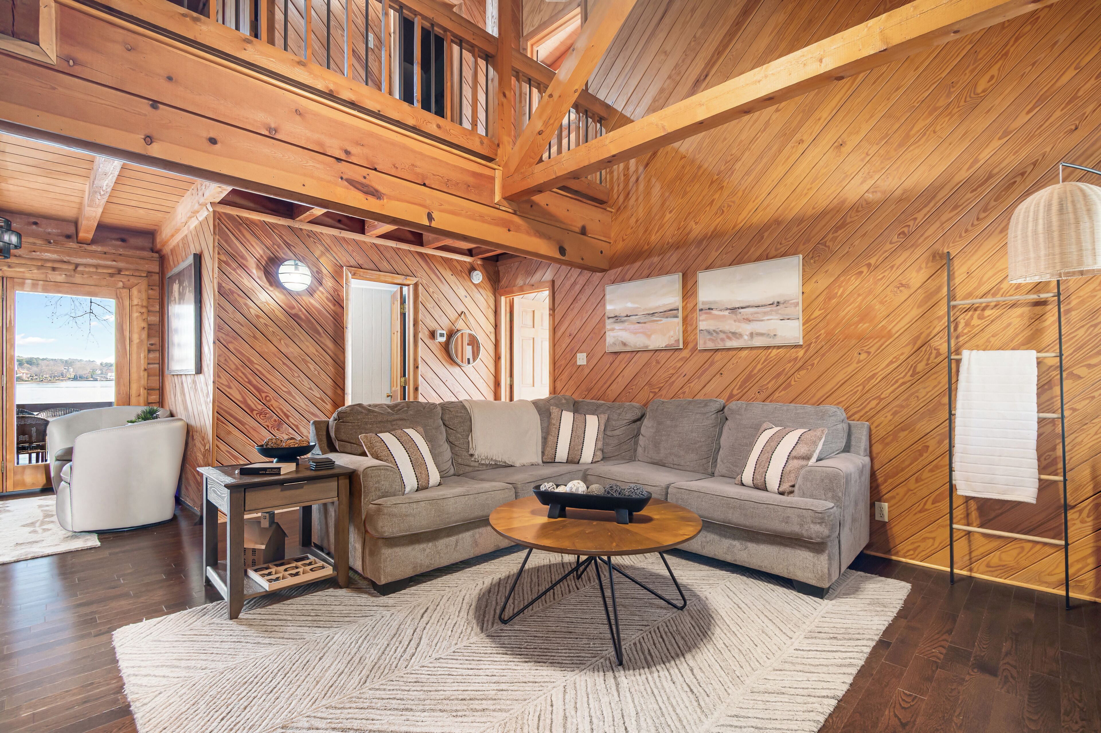 A cozy living room with a wooden ceiling, a sectional sofa, a coffee table, and a rug.
