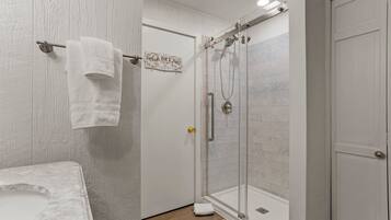 Une salle de bain avec une douche, un porte-serviettes avec une serviette, et une pancarte sur la porte.