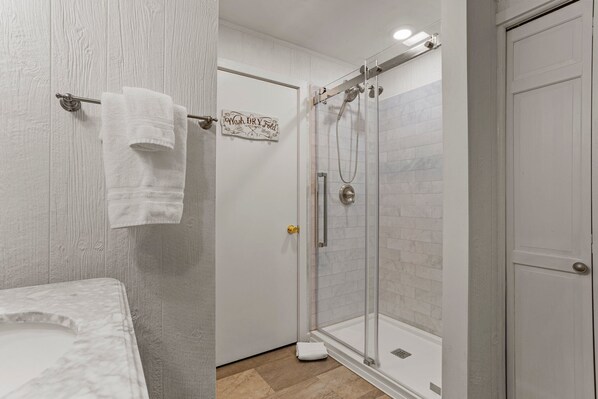 Un baño con ducha, un perchero con toalla y un cartel en la puerta.