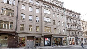 Un immeuble à plusieurs étages abritant différents commerces, notamment une parfumerie et une boutique de vêtements.