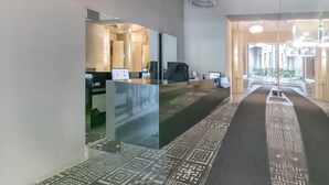 Un hall d’hôtel moderne avec un comptoir d’accueil, un grand miroir et une moquette à motifs.