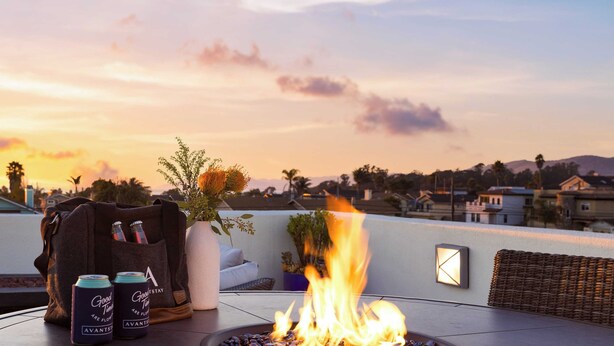 Feuerszene mit Getränken auf einer Dachterrasse bei Sonnenuntergang.