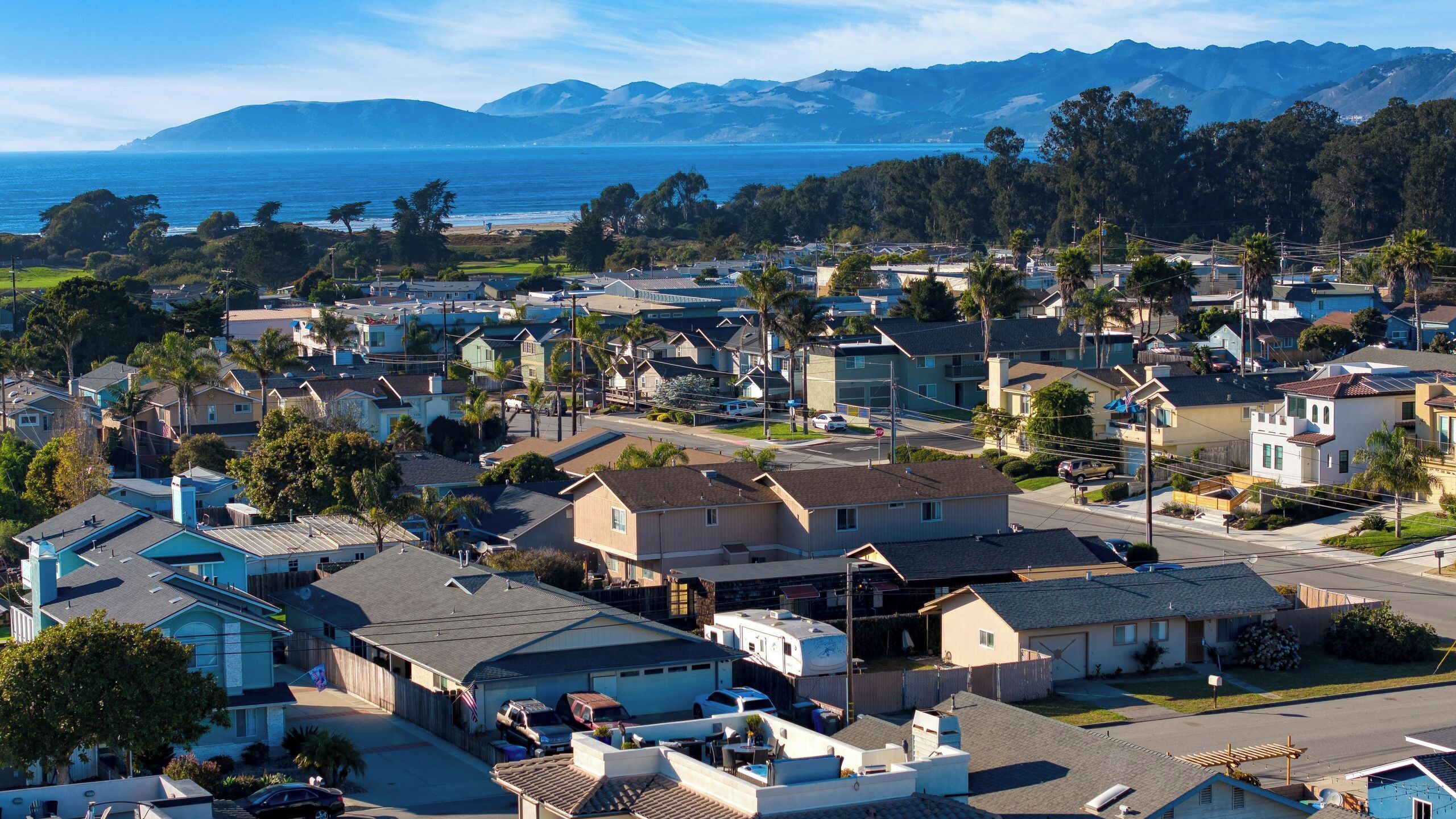 A residential area with houses, a street, and a view of the ocean.