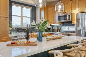 Una cocina moderna con armarios de madera, electrodomésticos de acero inoxidable, encimera de mármol y una isla central con asientos.
