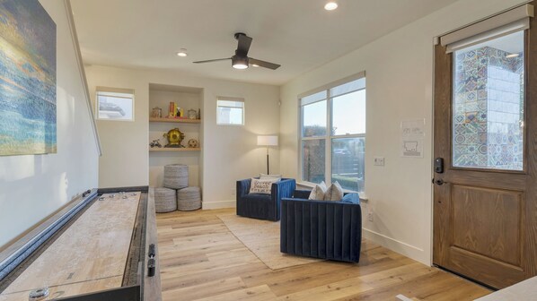 A room with a billiards table, a ceiling fan, a sofa, and a door with patterned glass.