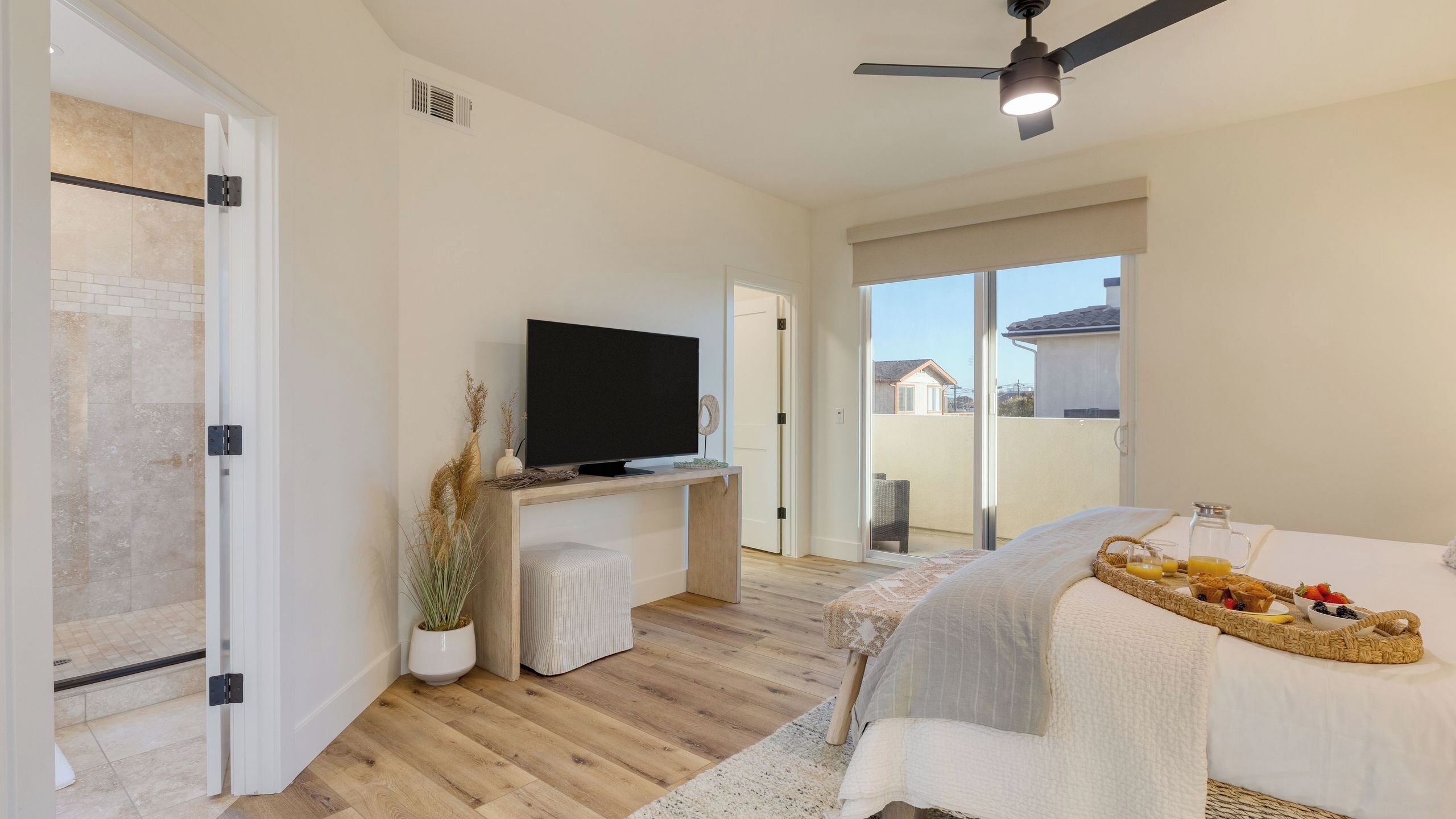 A modern bedroom with a TV, a bed, a balcony, and a breakfast tray.