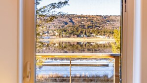 Une pièce avec une fenêtre donnant sur un lac et des collines.