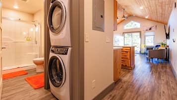 A laundry area with a washing machine and dryer, a shower, and a wooden floor.
