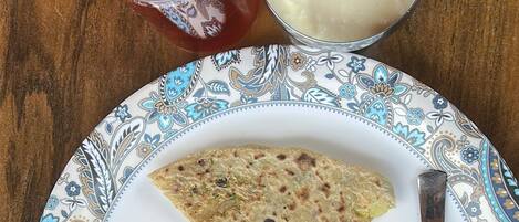 A plate with a flatbread, butter, and chutney on a patterned table.