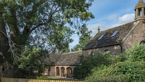A stone building with arched windows and a wooden fence. - 2 bedroom accommodation in Forfar (Forfar)