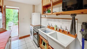 A compact kitchen with a washing machine, a microwave, and a sink. - 2 bedroom accommodation in Forfar (Forfar)
