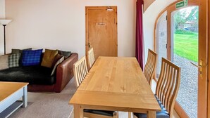 A room with a wooden table and chairs, a leather sofa with cushions, a door labeled "Private," and a window with a view of greenery. - 2 bedroom accommodation in Forfar (Forfar)
