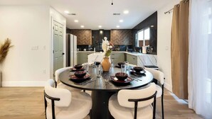 A modern dining area with a round table, chairs, and a ceiling fan.