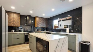 A modern kitchen with a central island, built-in oven, and a microwave.