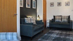 Ein Wohnzimmer mit zwei Sofas, einem Couchtisch, einer Lampe und gerahmten Bildern an der Wand.
