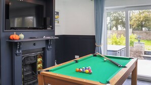 Ein Billardtisch mit Kugeln, ein Kamin und ein Fernseher.