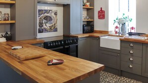 Eine moderne Küche mit einer Holzausziehtafel, einem Herd, einer Mikrowelle und einem Spülbecken.