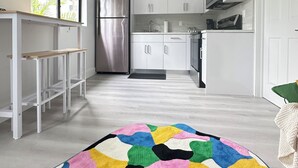 A modern kitchen with white cabinets, stainless steel appliances, and a colorful rug. - Charming 1-bedroom apartment with AC, WiFi in Heart of Miami (Miami)