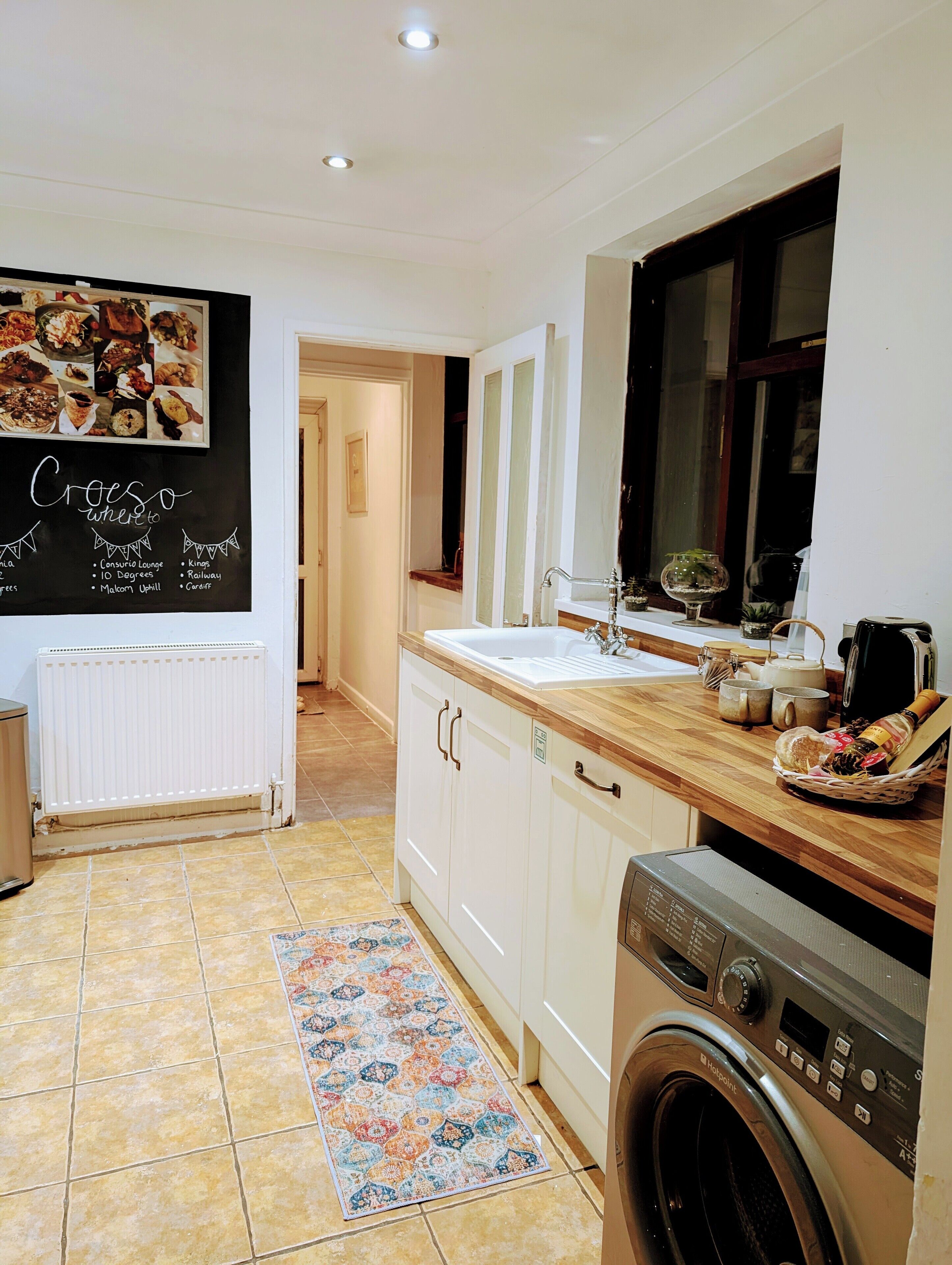 A kitchen with a white countertop, a sink, a washing machine, and a radiator.