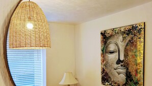 A room with a round mirror reflecting a lamp, a chair, a window with blinds, and a wall-mounted painting. - Ty Hiraeth 

A Charming Stay Steps Away from Caerphilly Castle!
 (Caerphilly)