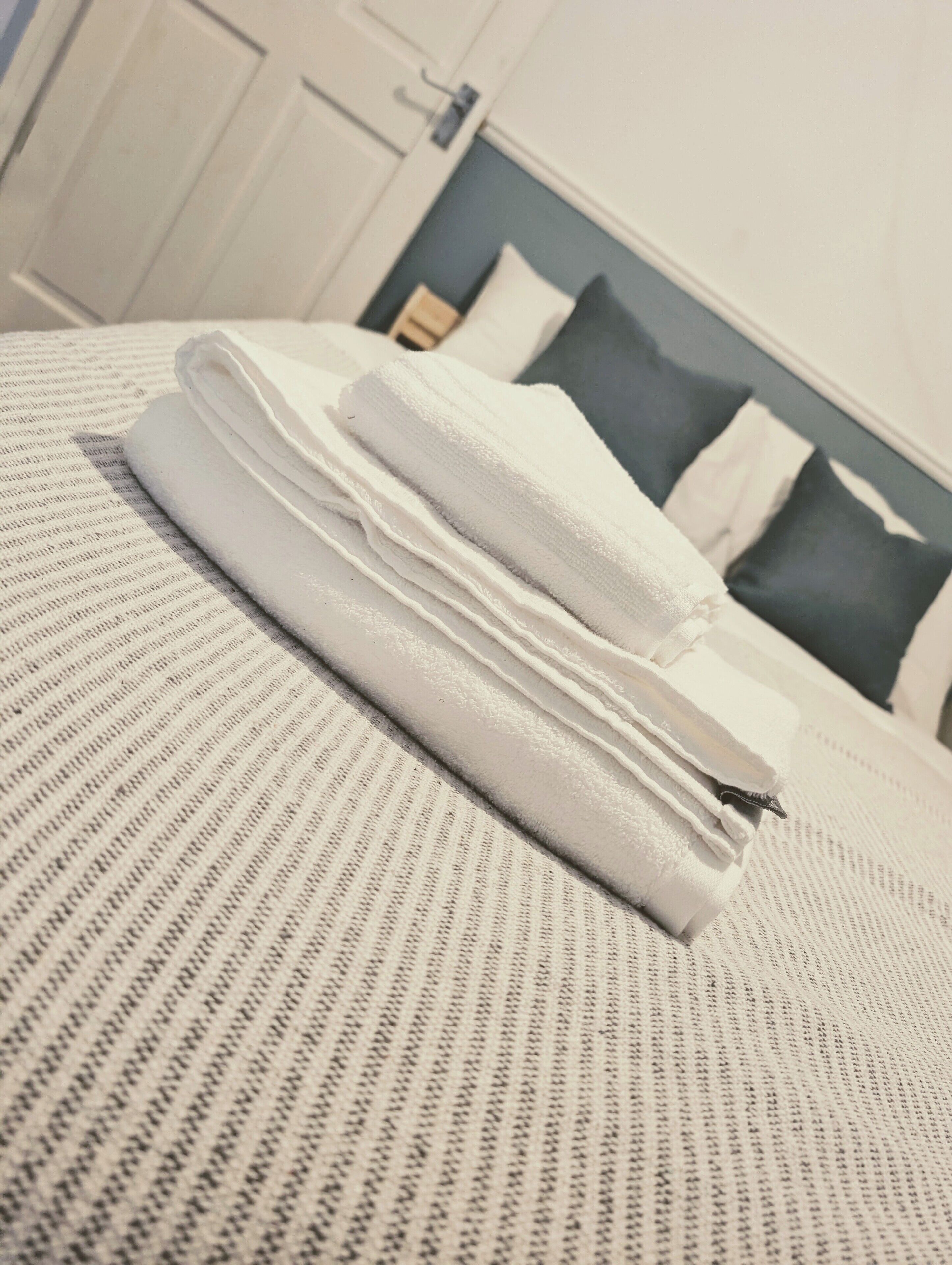 A neatly made bed with a striped bedspread and folded white towels.