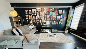 Uma sala de estar moderna com um sofá seccional, uma mesa de centro de vidro e uma parede decorada com obras de arte emolduradas.