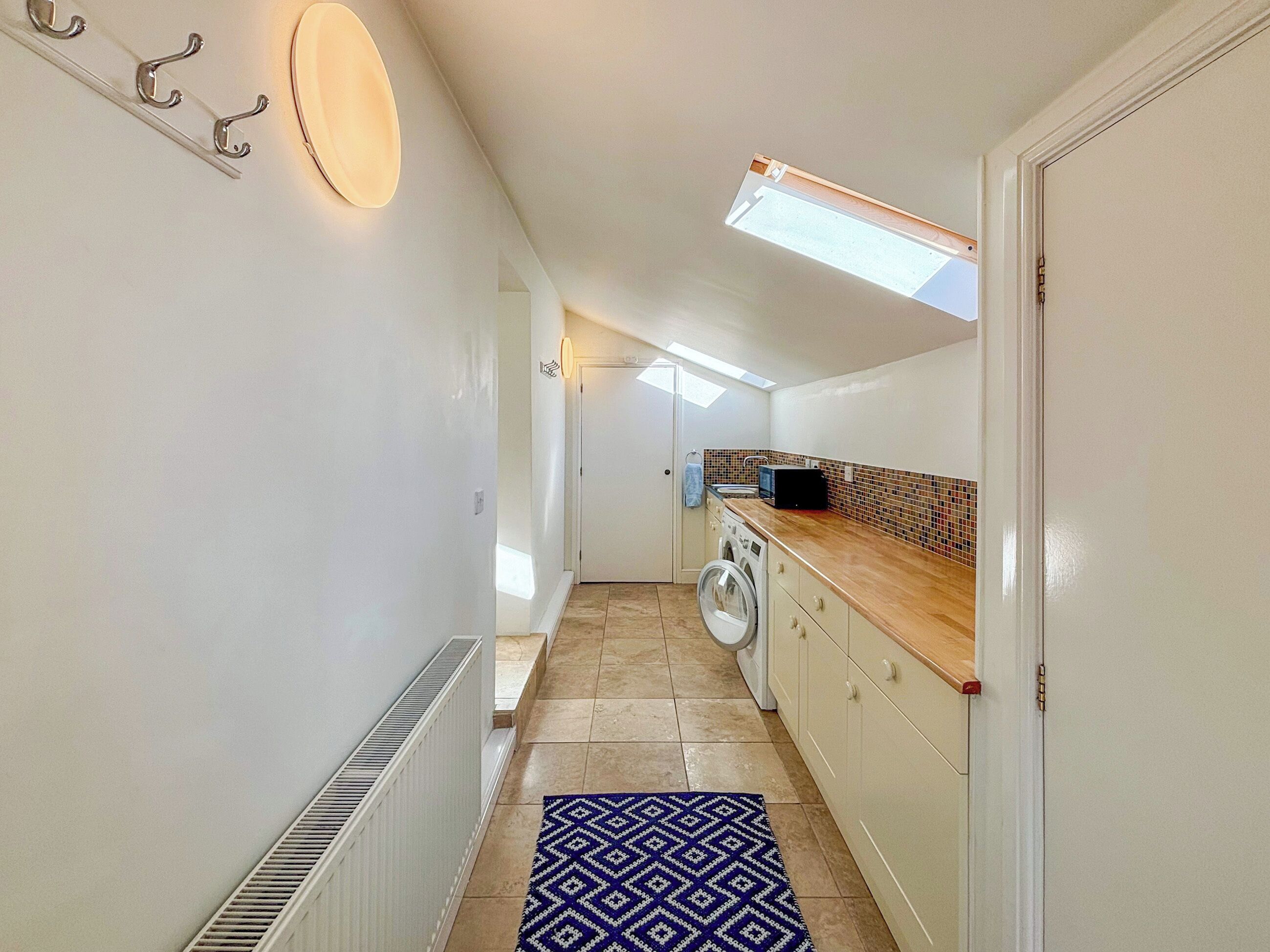 A narrow hallway with a washing machine, a radiator, and a patterned rug.