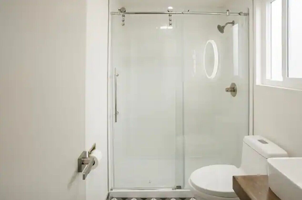 Un baño moderno con cabina de ducha de vidrio, inodoro y lavamanos.