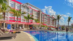 Un hotel con piscina, palmeras y zonas de estar al aire libre.