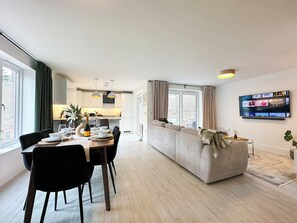A modern living space with a dining area, kitchen, and seating area.