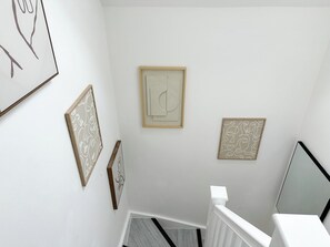 Una escalera con barandilla blanca, una obra de arte abstracta enmarcada y un diseño geométrico en la pared.