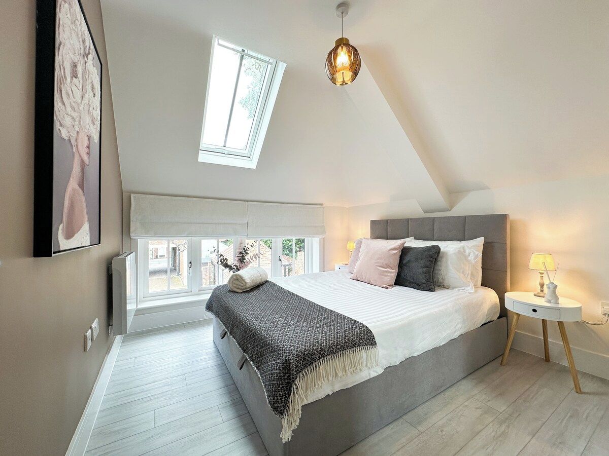 A bedroom with a bed, bedside table, lamp, and a window.