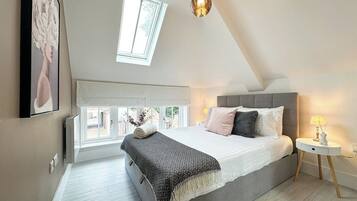 A bedroom with a bed, bedside table, lamp, and a window.