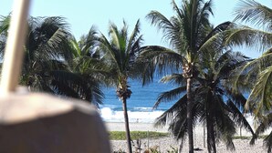 A beach view with palm trees and a drink in the foreground. - Mantra Hotel Boutique (Brisas de Zicatela)