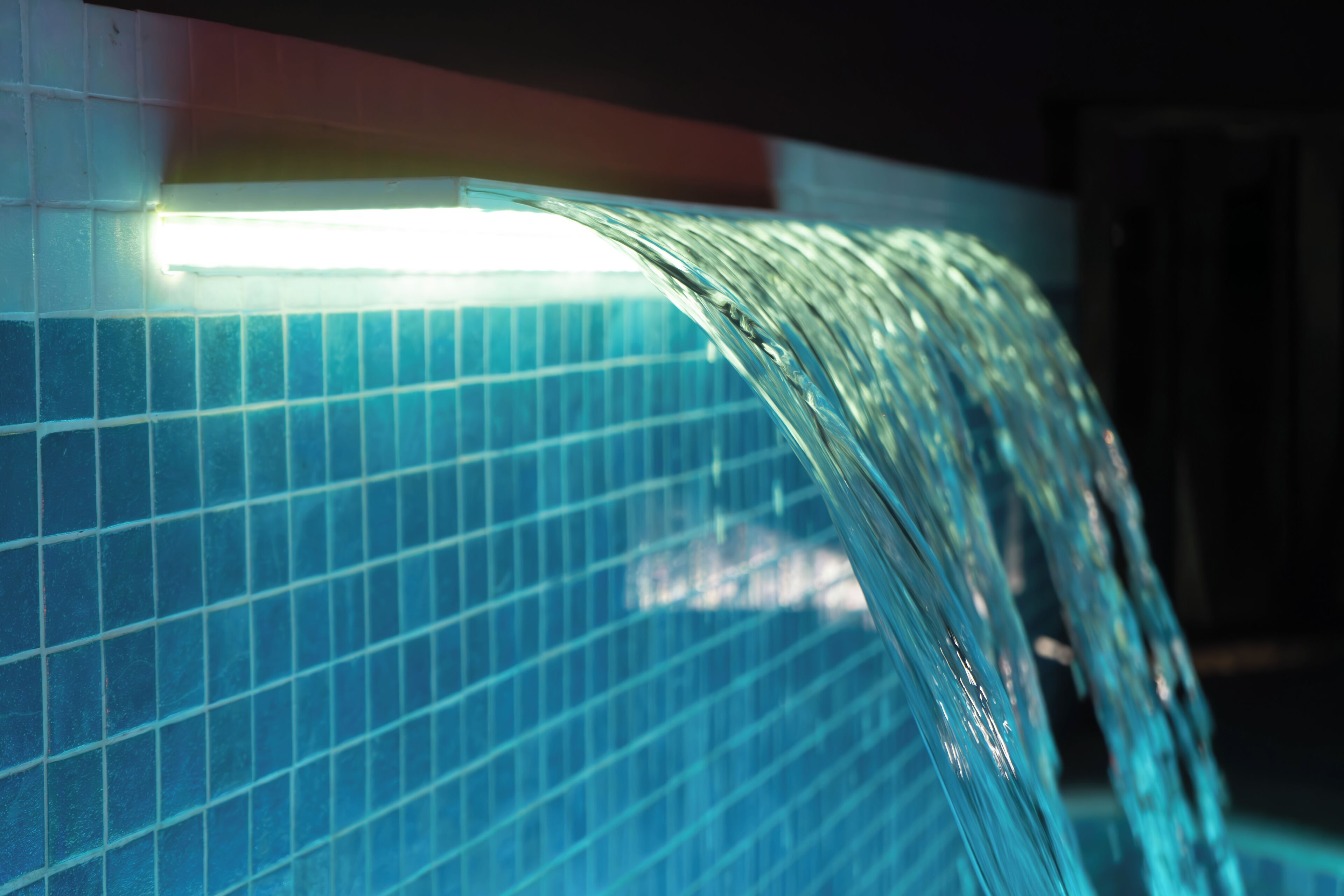 A close-up of a curved glass partition with a grid pattern, likely part of a pool or water feature.