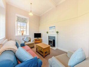 Una sala de estar con sofá, televisión, chimenea y ventana con vistas.