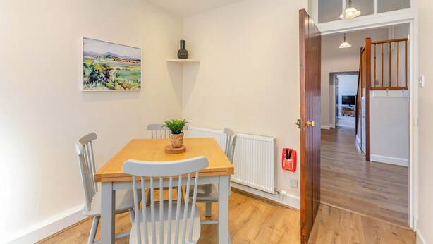 A dining area with a table, chairs, a plant, a radiator, and a fire extinguisher. - The Old Bakery - UK48319 (Berwick-Upon-Tweed)