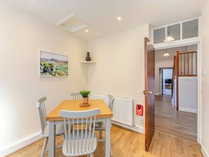 Un espace repas comprenant une table, des chaises, une plante, un radiateur et un extincteur.