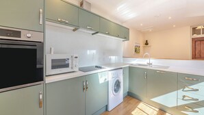 A modern kitchen with built-in appliances, a washing machine, and a sink. - The Old Bakery - UK48319 (Berwick-Upon-Tweed)