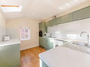Une cuisine compacte dotée d’un four, d’un micro-ondes et d’un lave-vaisselle intégrés, d’un plancher en bois et d’une fenêtre offrant une vue agréable.